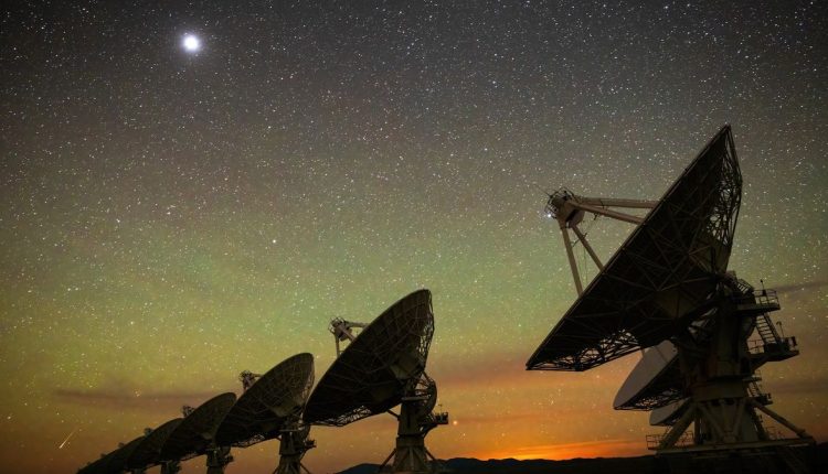 An image of the Very Large Array at night, with the large radio antenna dishes silhouetted against a starry background. Credit: Bettymaya Foott, NRAO/AUI/NSF